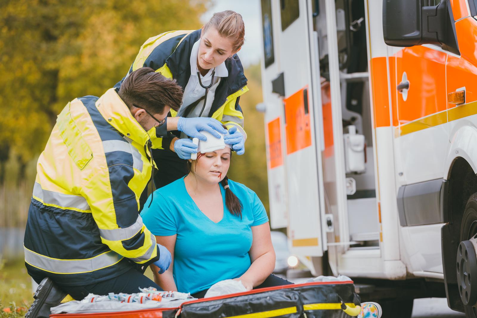 Emergency medics dressing head wound of injured woman