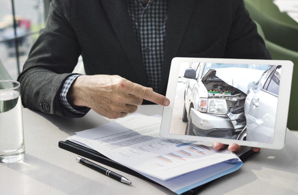 Insurance Agent showing image of accident for valid & maximum reimbursement of insured vehicle.