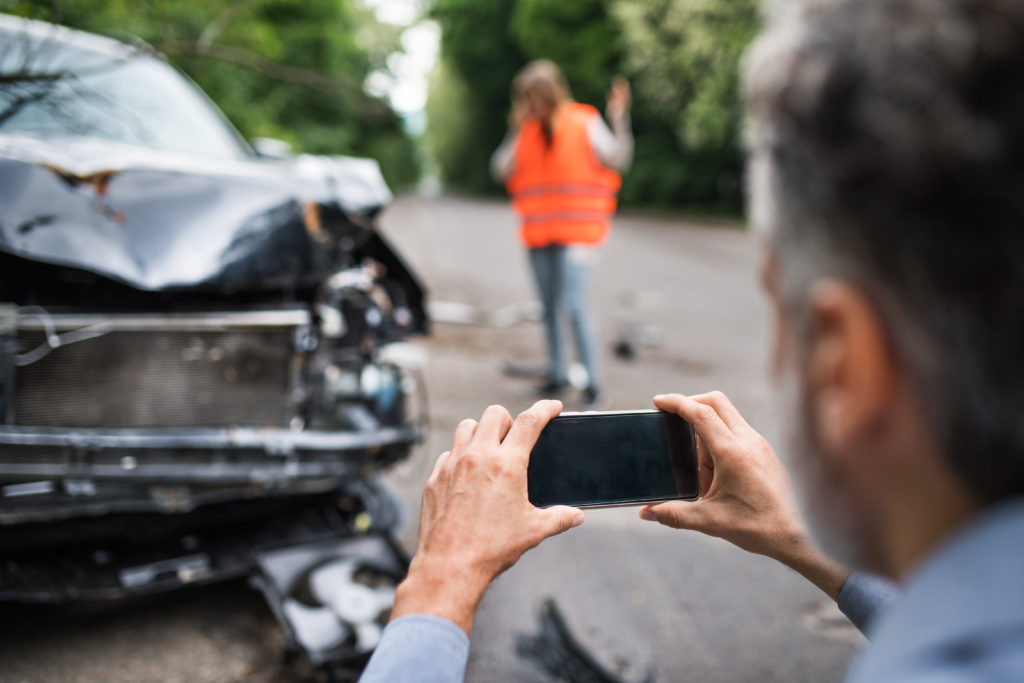 Person taking pictures of a broken car after an accident.